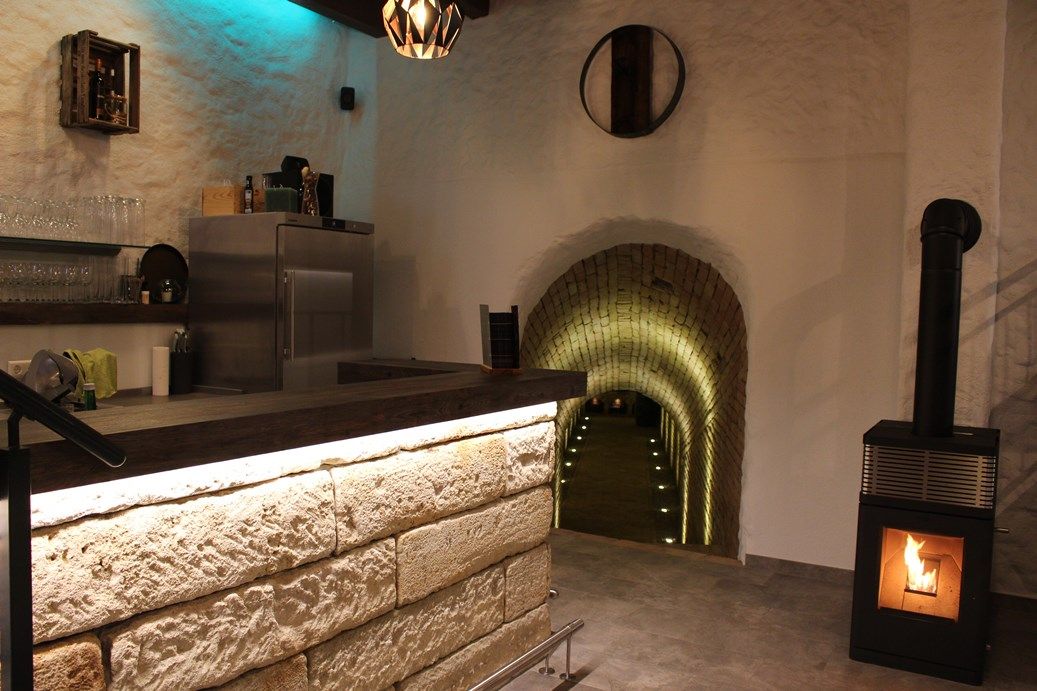Interior view of a wine bar with counter, fireplace and illuminated tunnel.