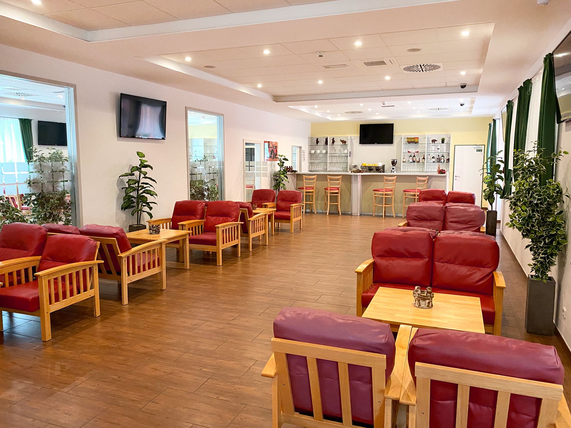 Bright lounge with bar and red, upholstered seating and small tables