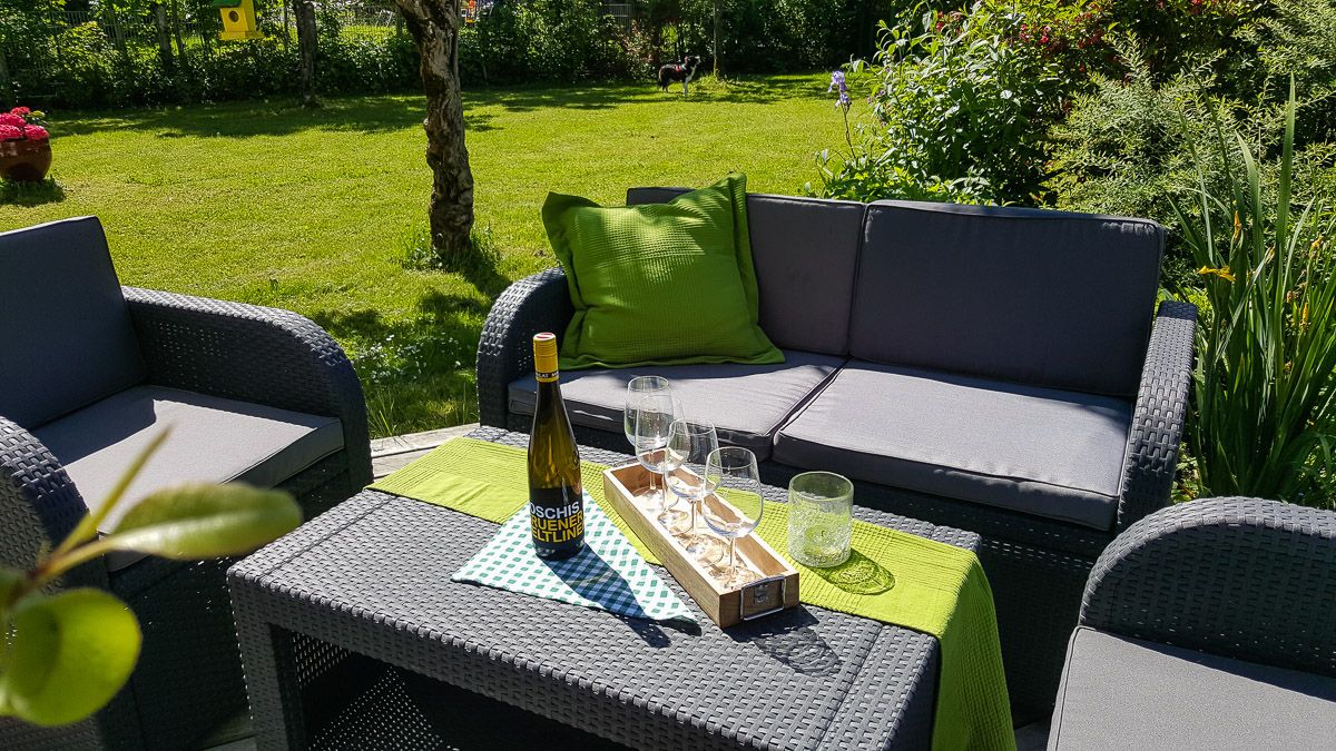 Garden furniture with wine bottle and glasses on an outdoor table.