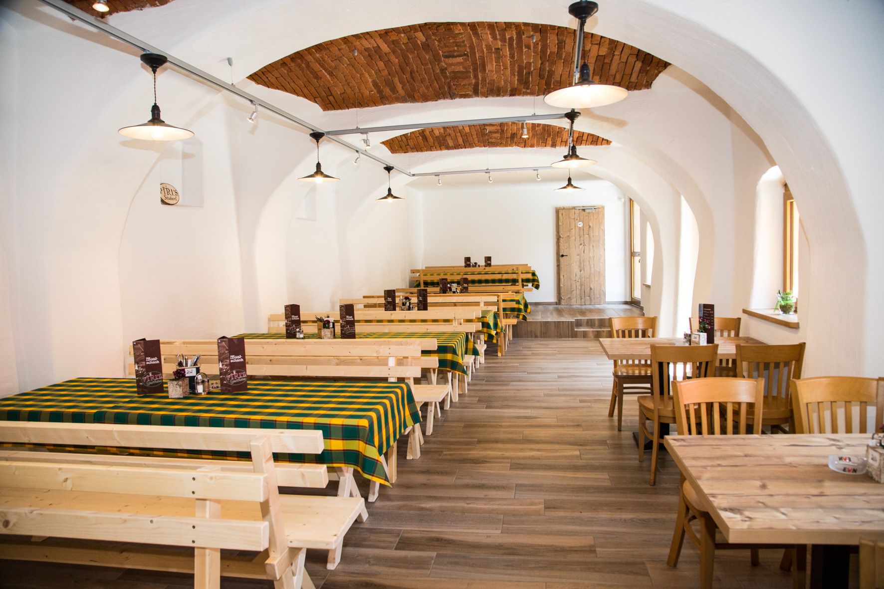 Traditional interior of an inn with wooden tables and checkered tablecloths.