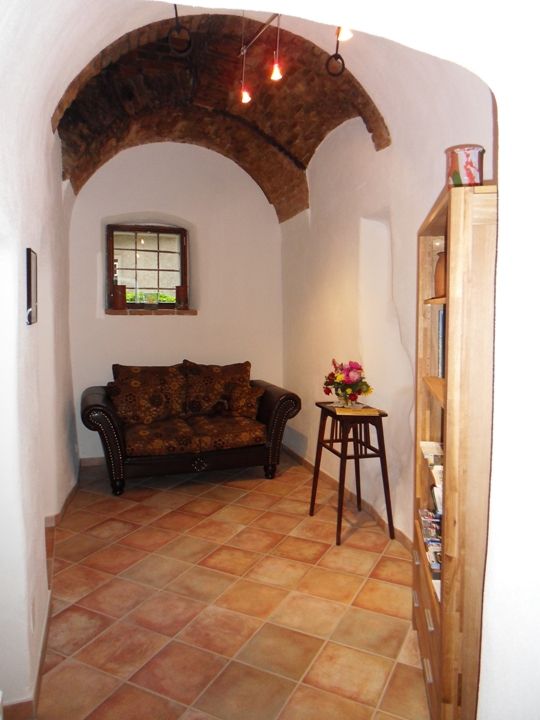 Historic room with terracotta tiles and a two-seater couch in dark brown.