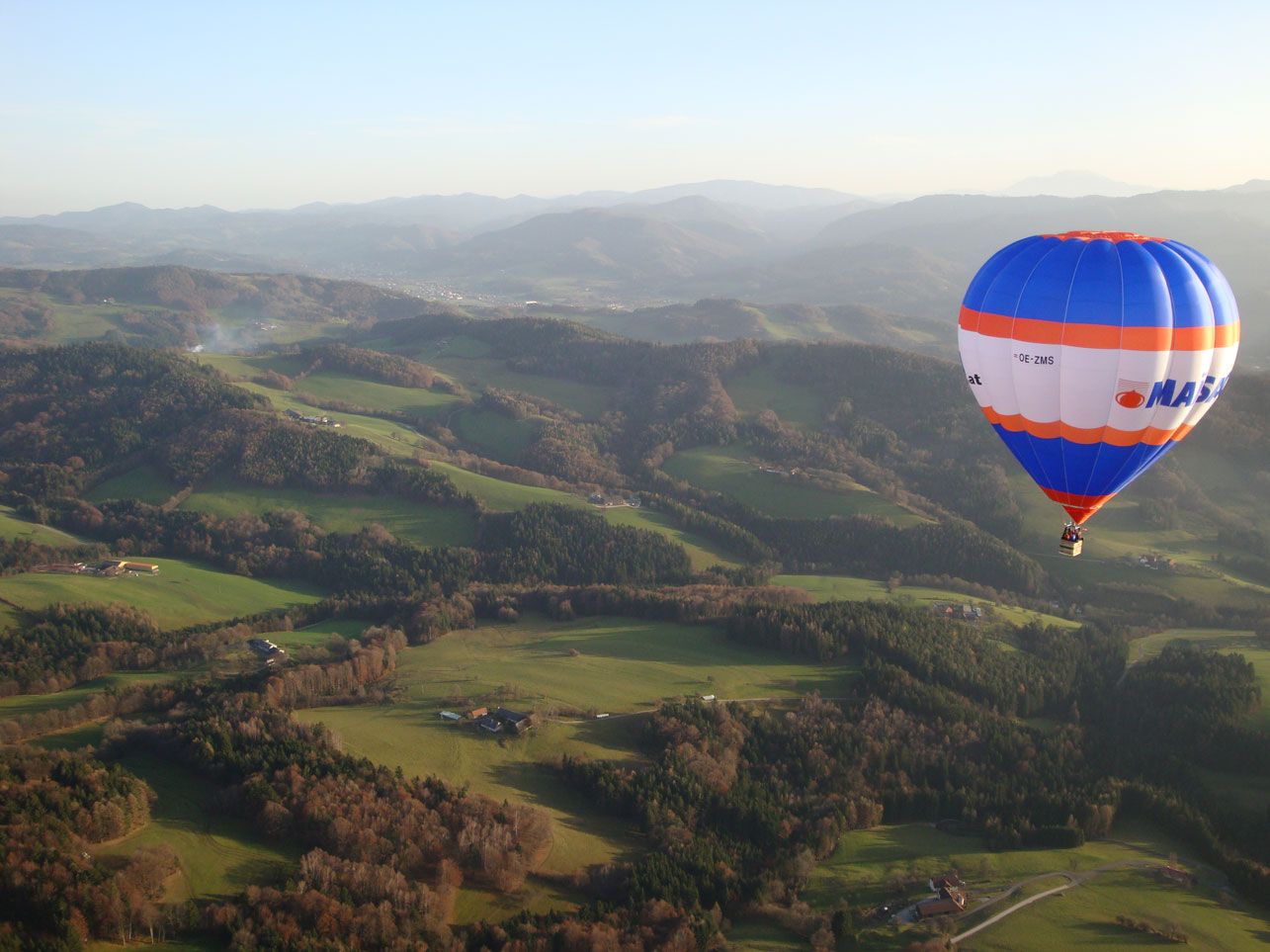 Hot air balloon over the green hilly landscape of the Traisental.