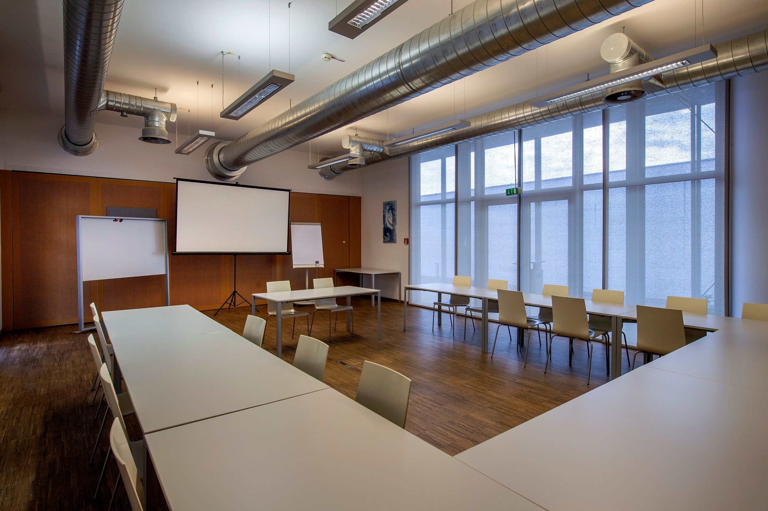 Seminar room with tables, chairs and projection screen.