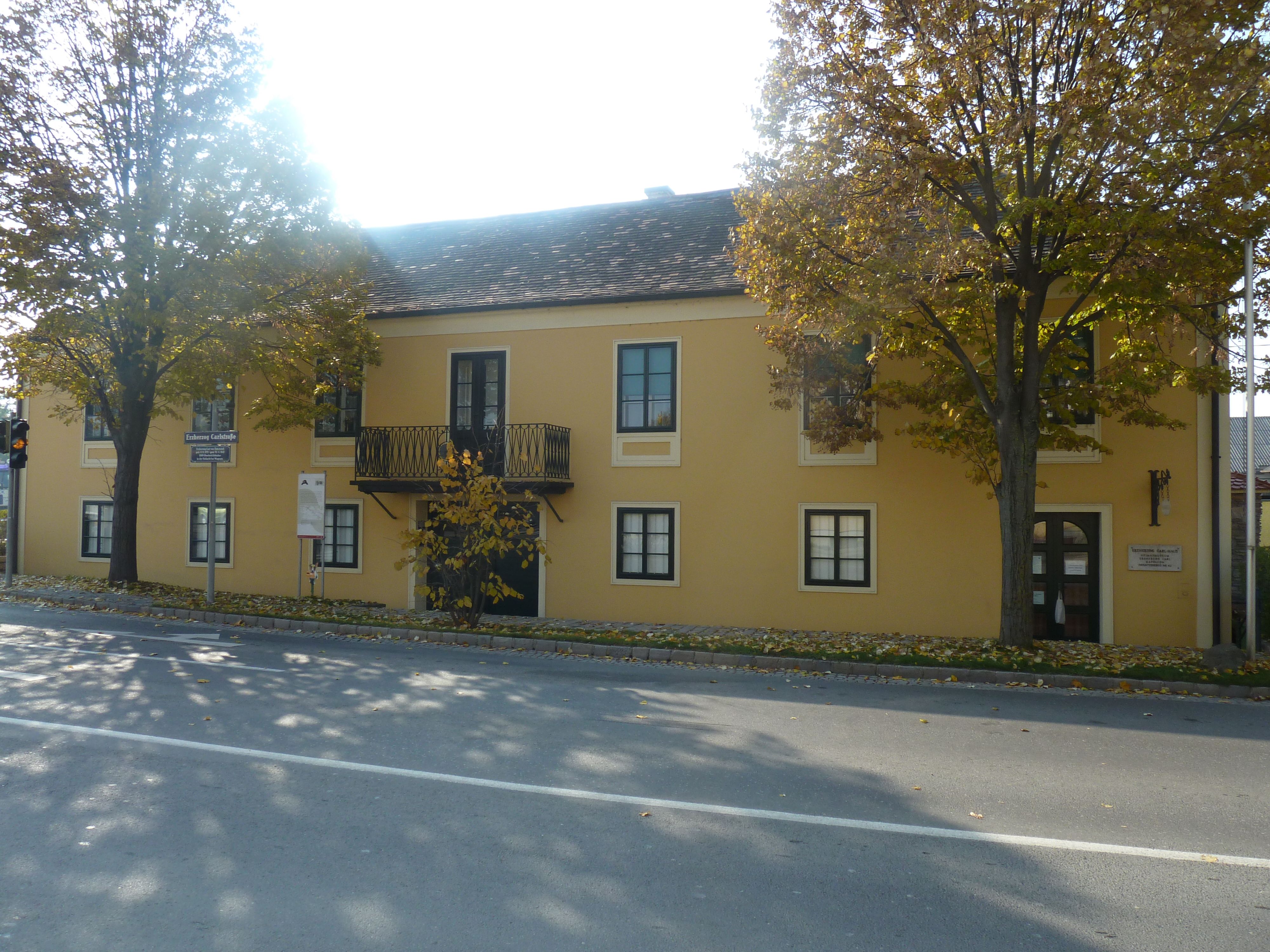 Yellow building with balcony and trees in front, Archduke Carl House and Napoleon Museum in Deutsch-Wagram.