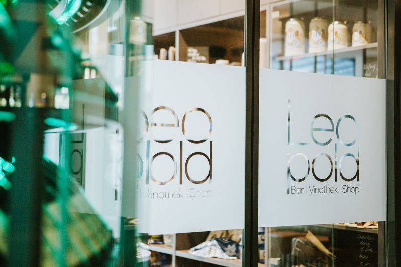 Entrance to the vinotheque with the lettering 'Leopold Bar Vinothek Shop' on the glass door.