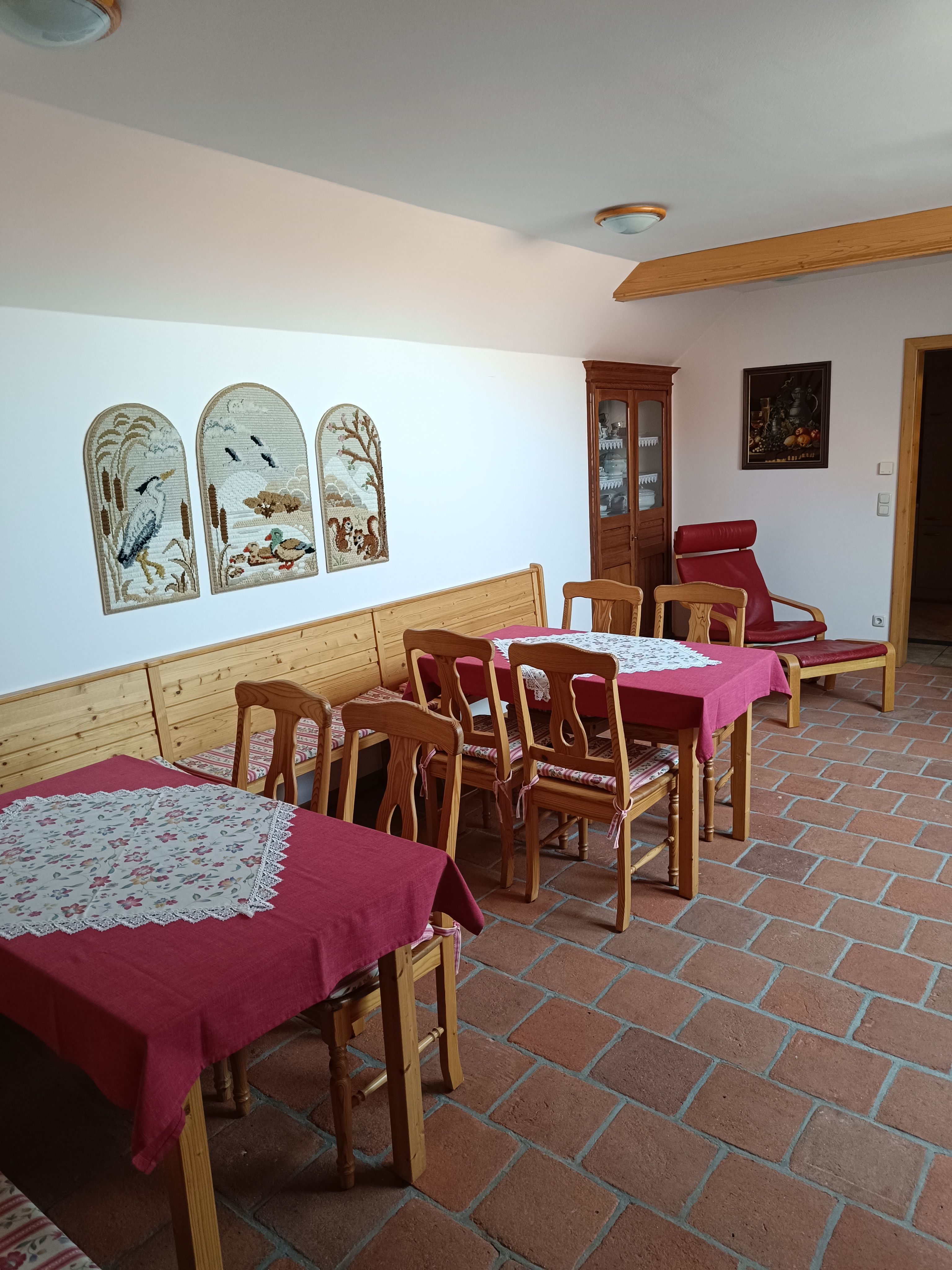 A cozy lounge with wooden furniture, red tablecloths and wall decorations.