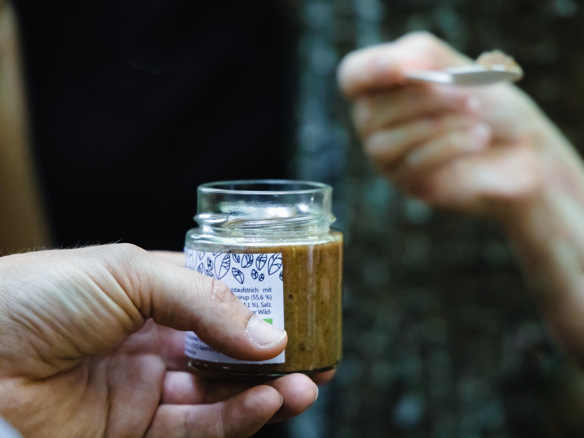 Ein köstliches Glas frischer Aufstrich wird in der Hand gehalten, während die Natur des Wienerwaldes im Hintergrund erblüht. Die harmonische Verbindung von Genuss und Landschaft lädt dazu ein, die Seele baumeln zu lassen und die Schönheit der Umgebung zu genießen.