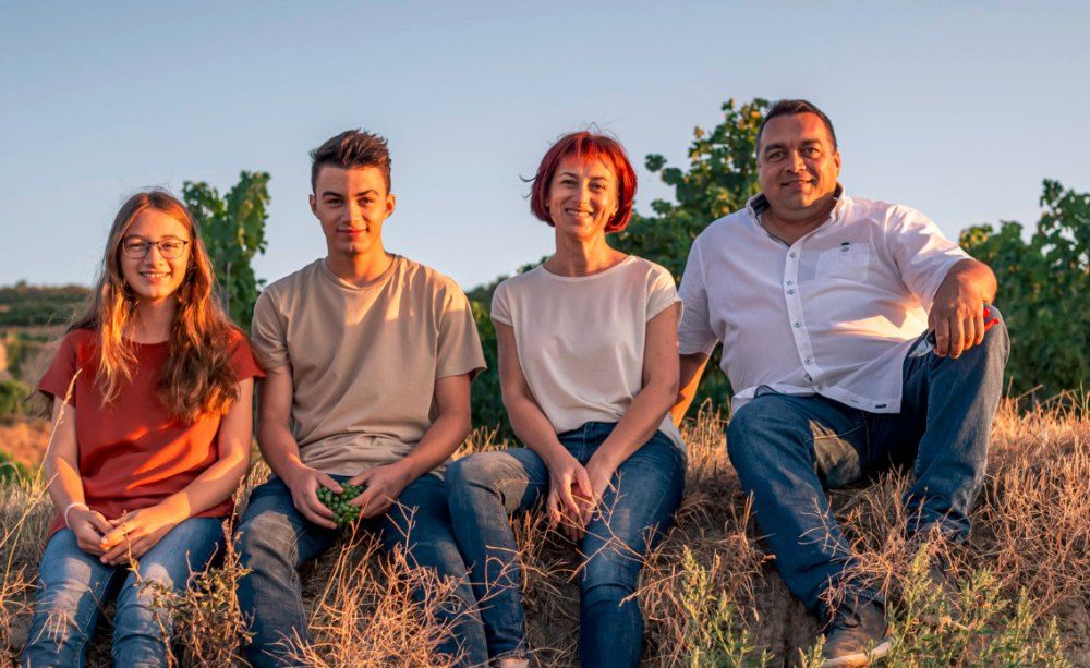 Four people sitting in a field at sunset.