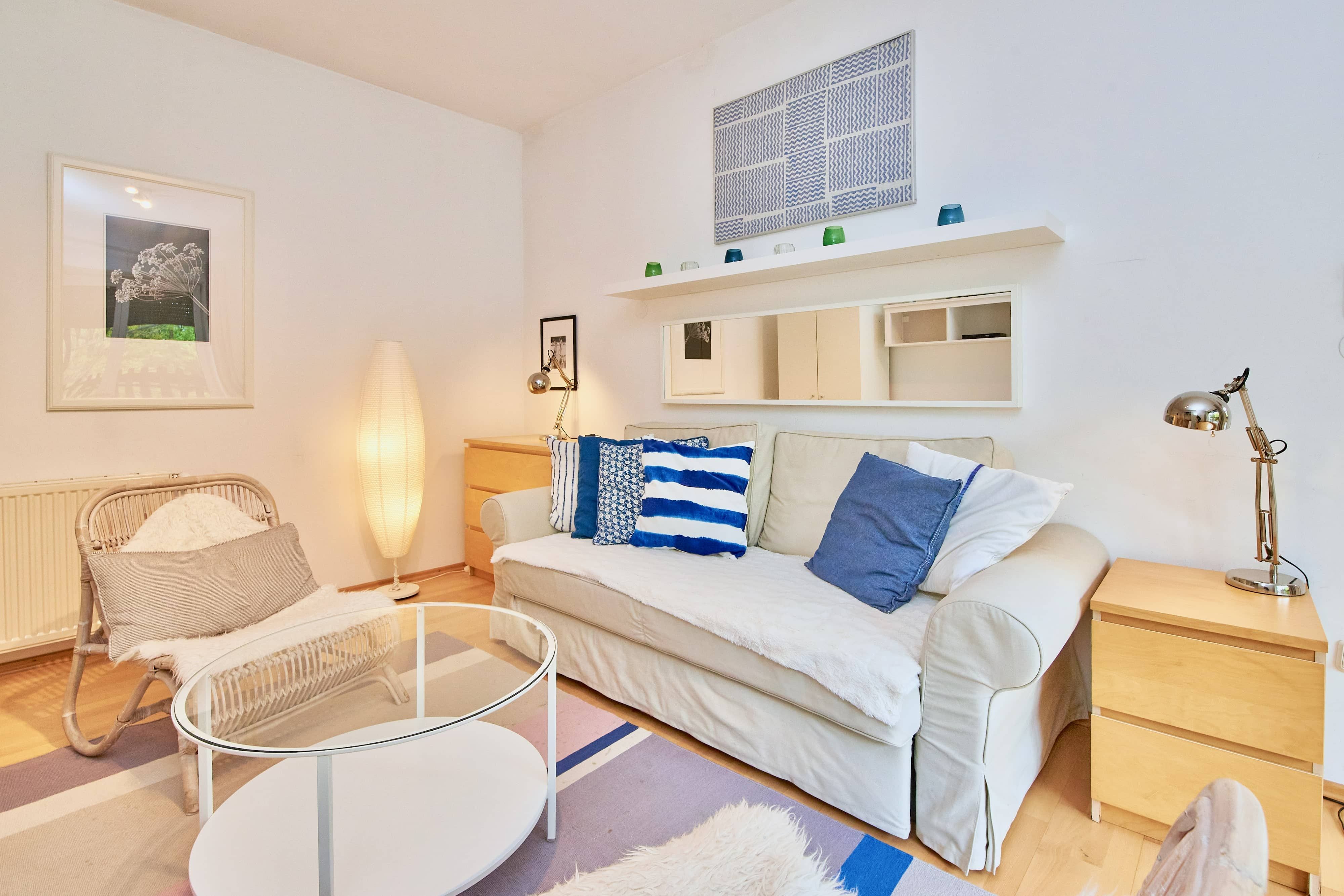 Cozy living room with sofa, cushions, armchair, floor lamp and coffee table.