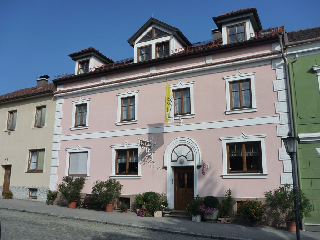 Exterior view of a pink house with white window frames and a yellow flag.