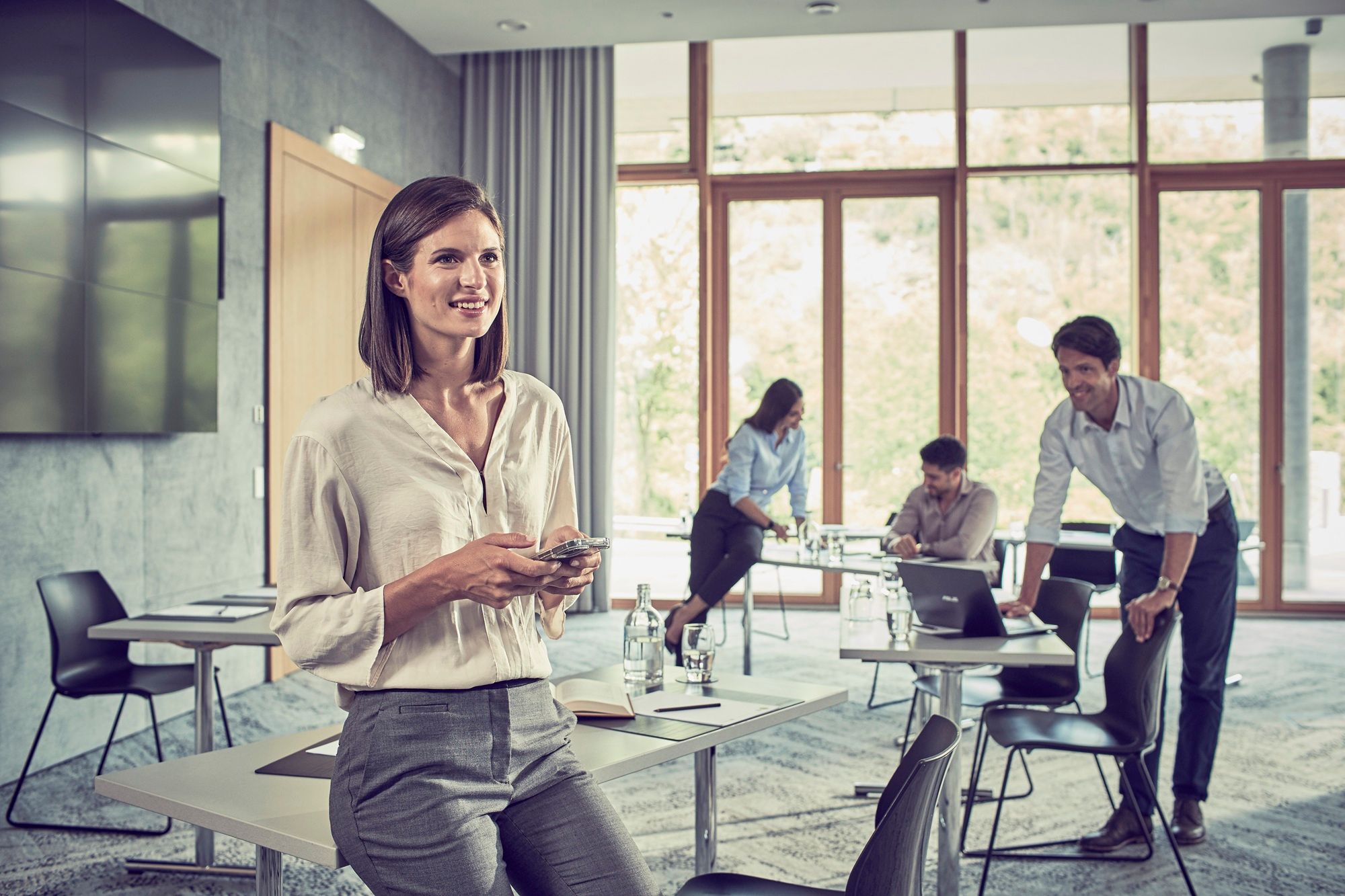 Meeting room in the Steigenberger Hotel in Krems, a woman sitting on a desk with a mobile phone