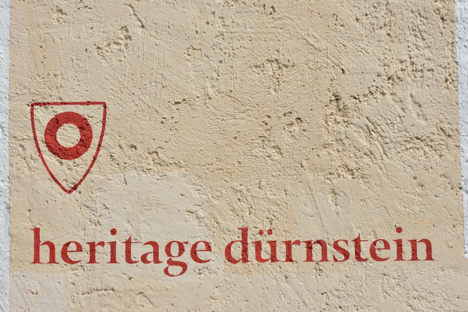 Wall with red lettering 'heritage dürnstein' and a red symbol.