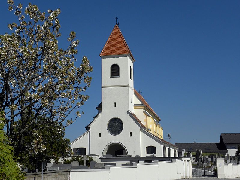 St. Anna church in Wiesmath with blue sky and blossoming tree in the foreground.