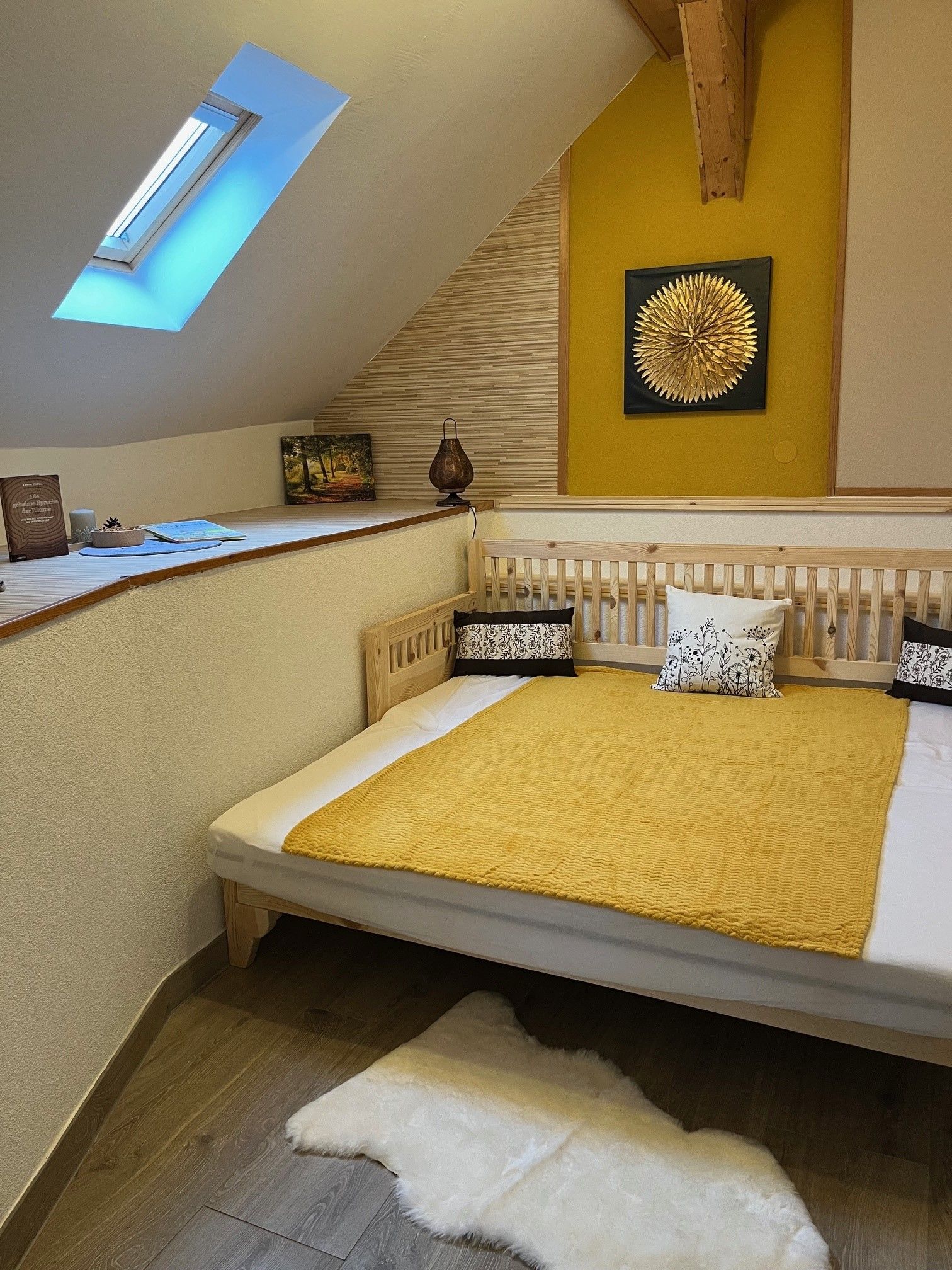 Cozy bedroom with skylight, yellow wall decoration and wooden bed.