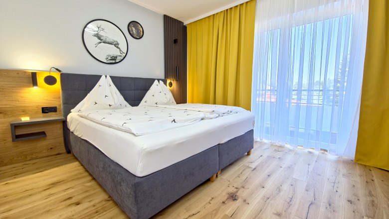 Modern bedroom with double bed, wooden floor and yellow curtains.