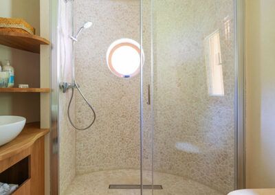 Modern shower with round glass wall and small porthole.