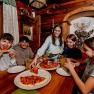Children eat pizza in a rustic room with wooden walls.
