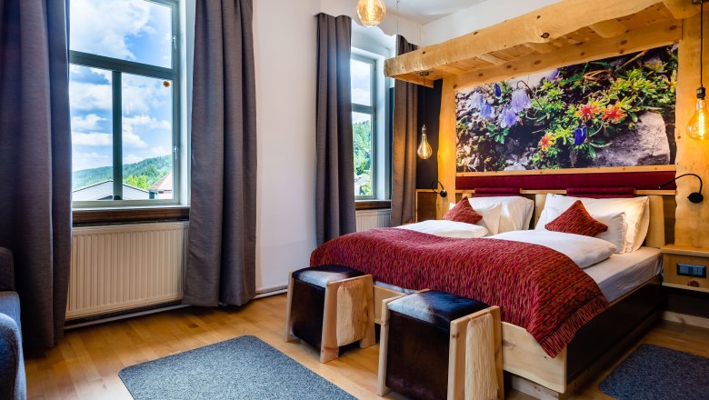 Comfortable hotel room with double bed, wooden furniture and large window with a view of nature.