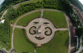 Aerial view of a garden with a facial pattern of plants and paths.