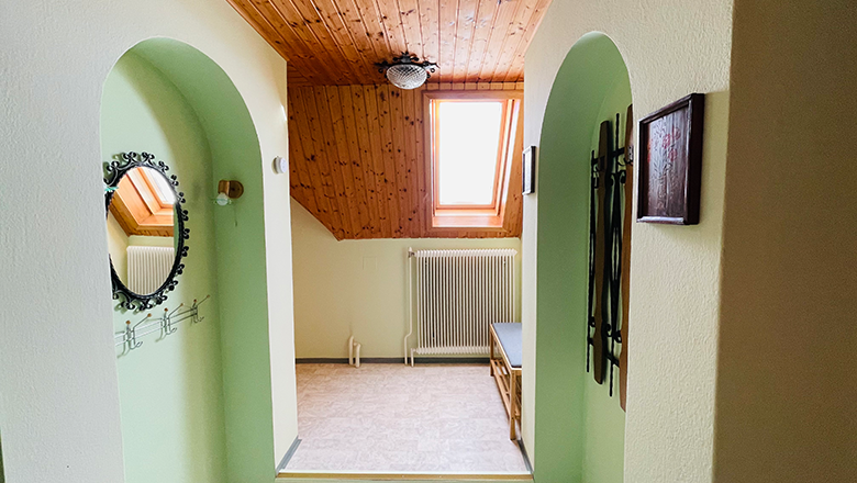 An anteroom with wooden ceiling, skylight, mirror and bench.
