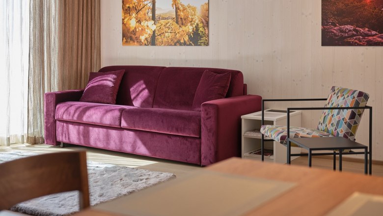 Living room with purple sofa, colorful chair and murals.