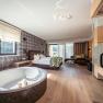 Luxurious hotel room with free-standing bathtub, large bed and panoramic window with a view of nature.