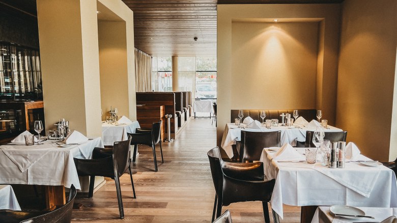 Elegant restaurant with laid tables and leather armchairs.