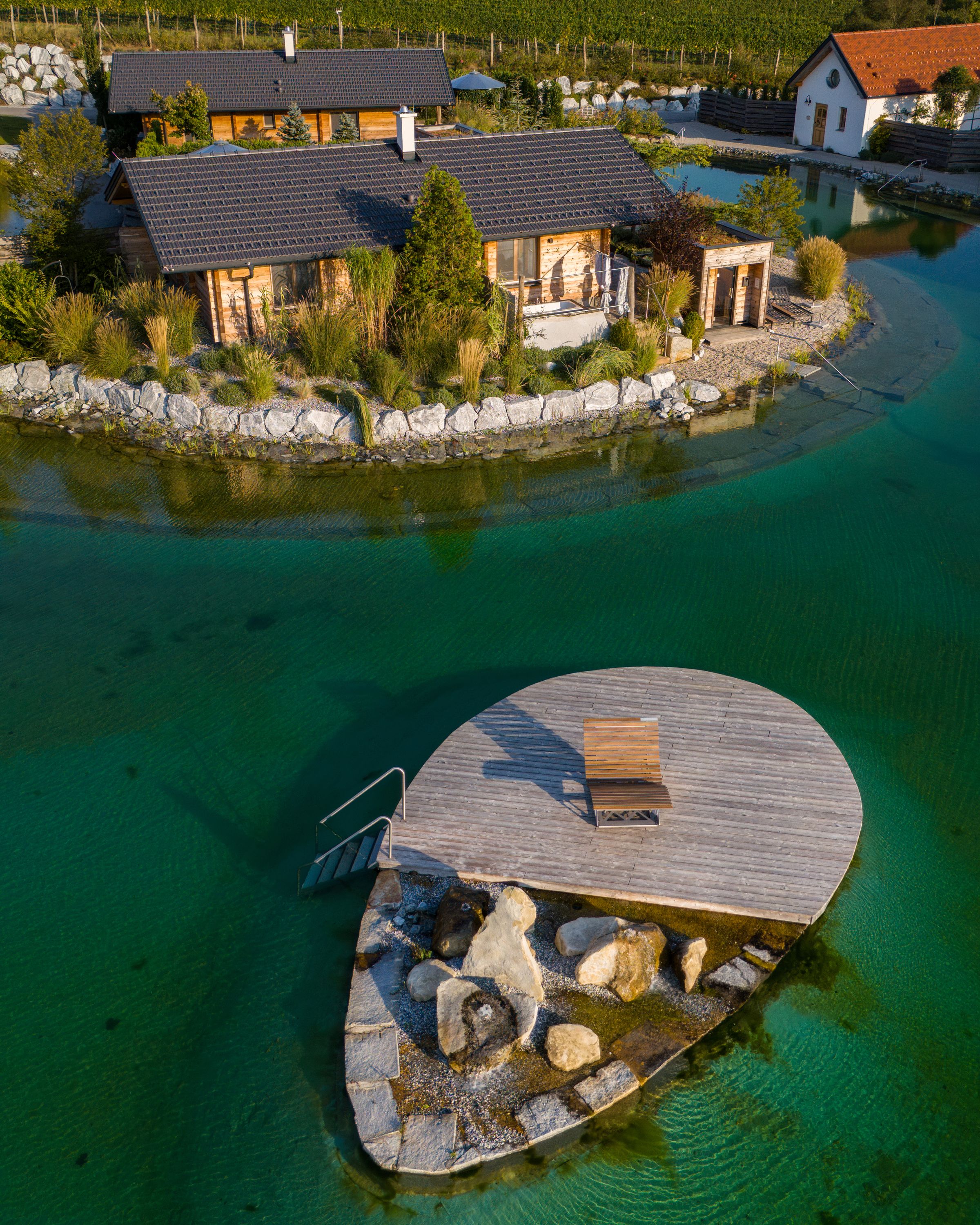 Aerial view of chalets on the garden lake with jetty and deckchair.