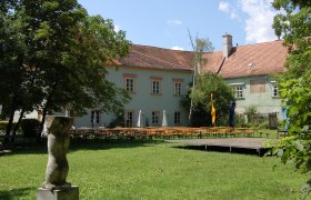 Bad Fischau Castle with garden and beer tables.