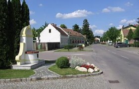 Street in Mitterndorf an der Fischa with houses and monument.