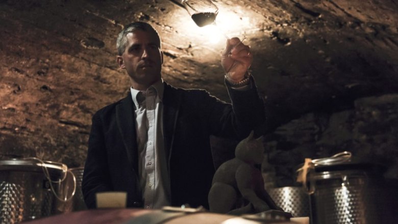 Person in the wine cellar holds a glass of wine against the light.