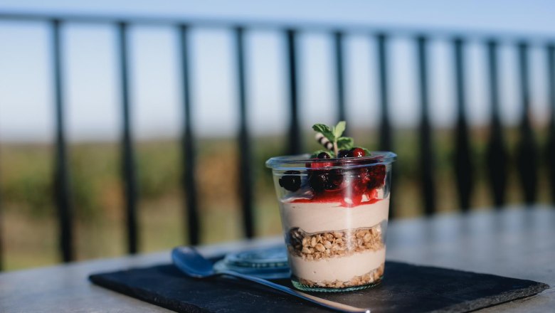 Dessert in a glass with berries and mint on a table with a blurred background.