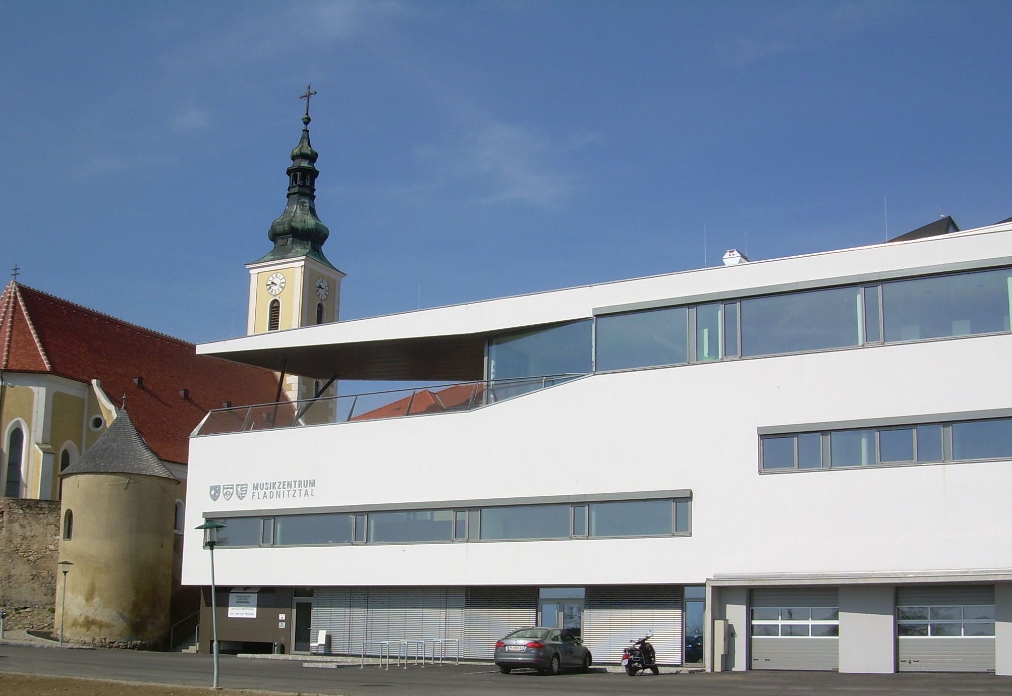 Modern building with church tower in the background in Wölbling.