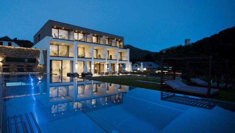 Modern boutique hotel with illuminated pool at night.