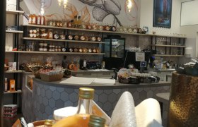 Interior view of a store with shelves full of liqueur bottles and jam jars.