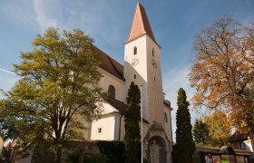 Church with tower and clock, surrounded by trees in the fall.