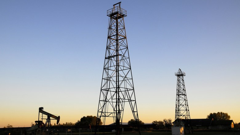 Two derricks and an oil pump at sunset.