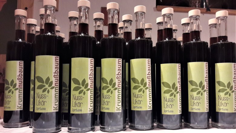 Row of bottles with nut liqueur and green labels.