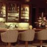 Elegant bar with wooden paneling, flower arrangements and upholstered bar stools.