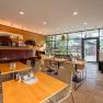 Interior view of a modern restaurant with wooden tables and large windows.