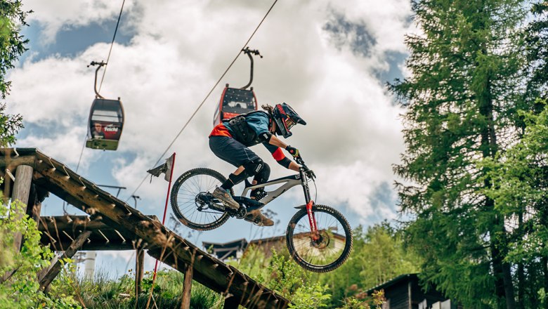 Mountain biker jumps off a ramp in Semmering Bike Park.