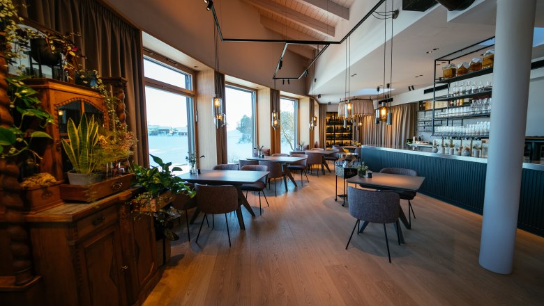 Elegant restaurant with wooden floors, large windows and stylish furnishings.