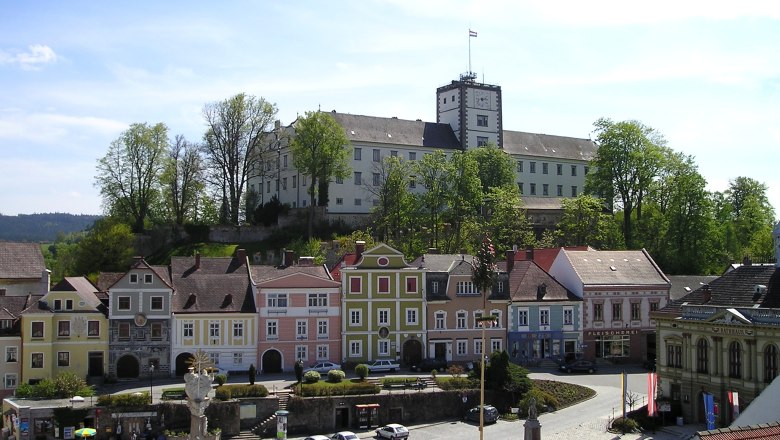 Weitra Castle overlooks the market square with colorful houses and a statue in Weitra, Austria.