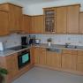 Modern kitchen with wooden cupboards, electrical appliances and sink.