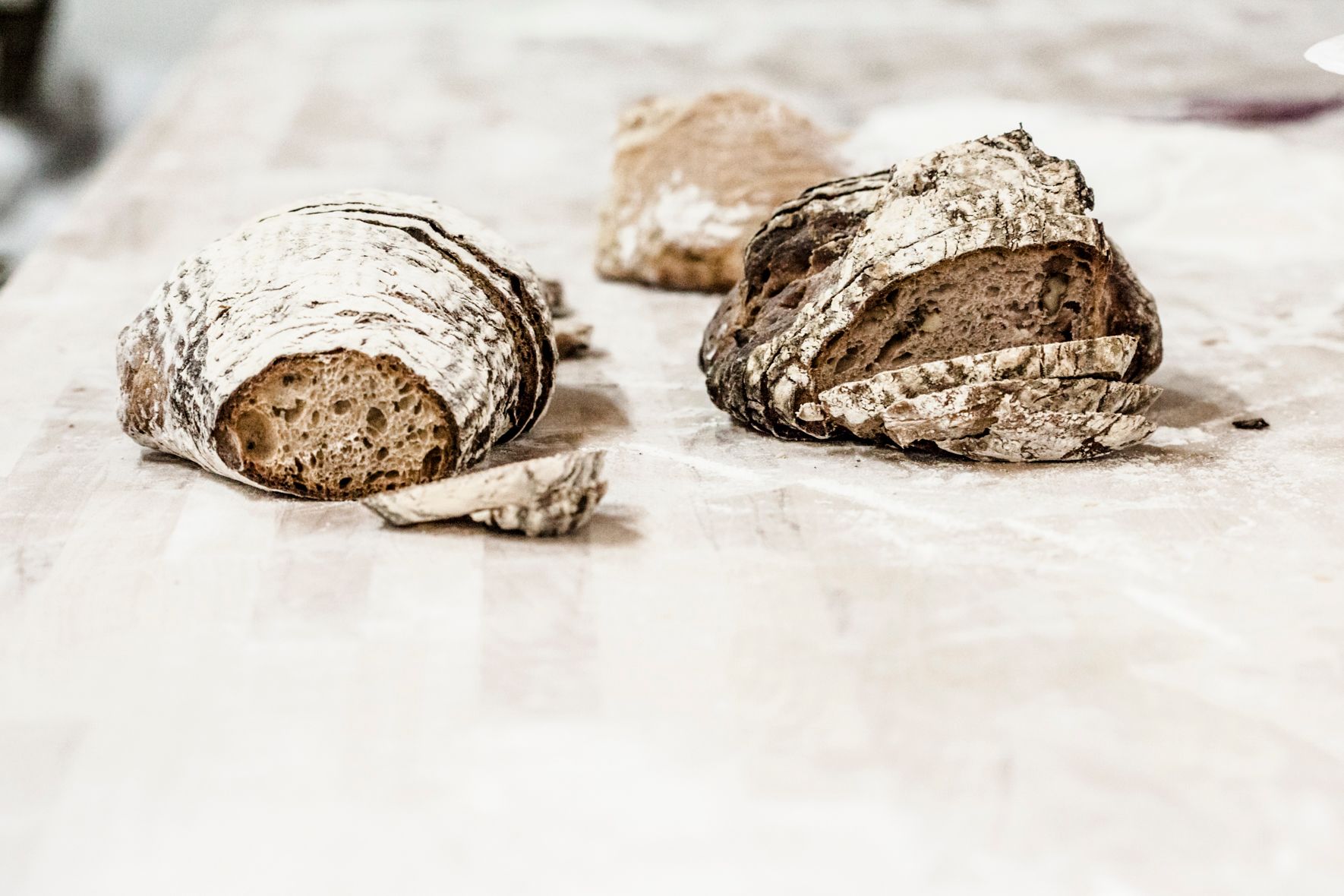 Two loaves of bread on a wooden table, partially sliced.
