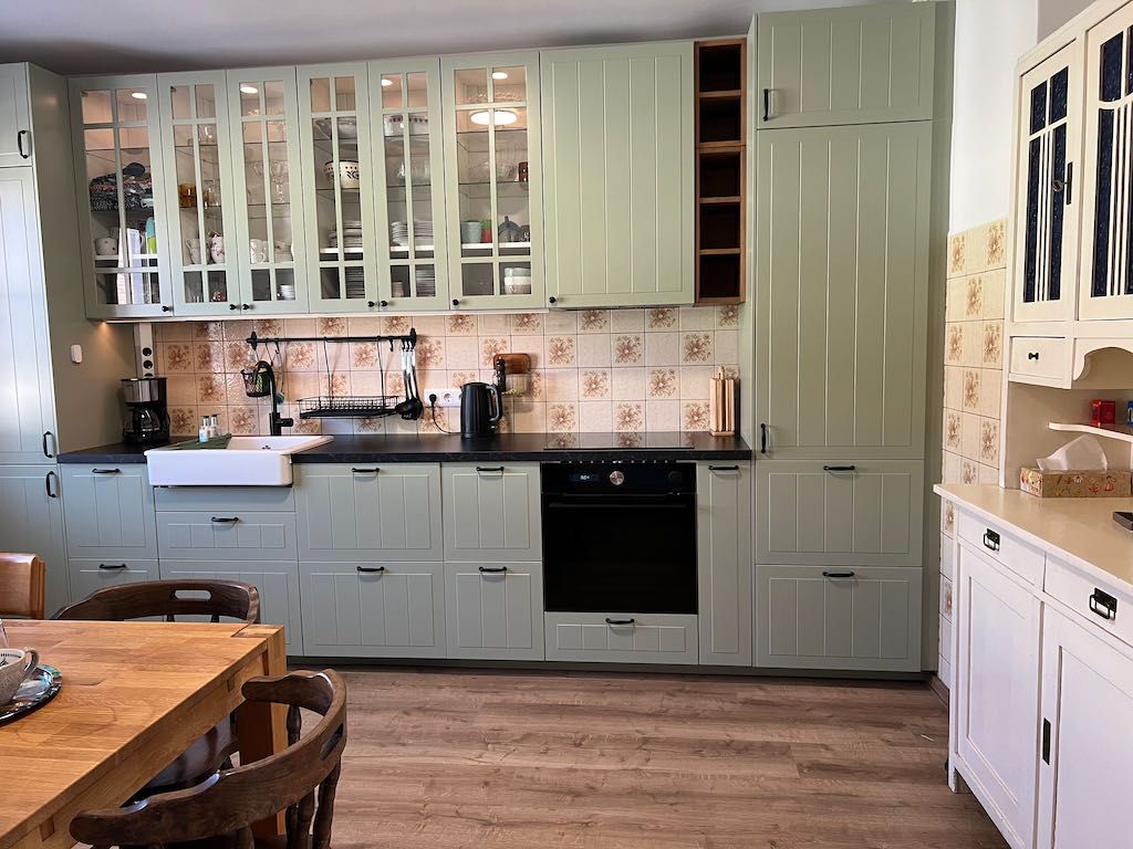 Kitchen with white cupboards, wooden worktop and tiled splashback.