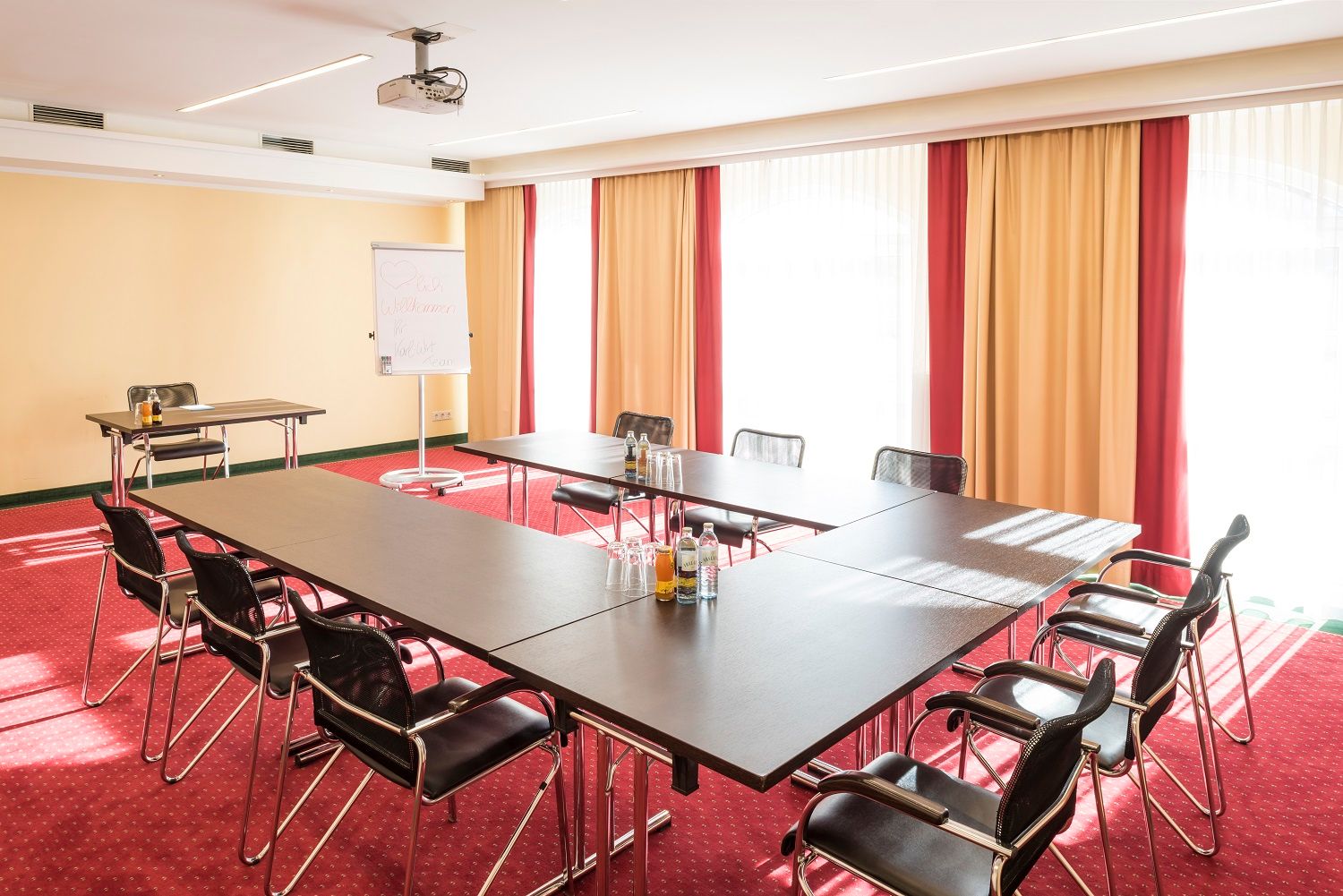 Conference room with U-shaped table, chairs, flipchart and projector.