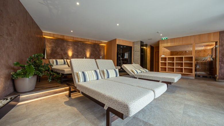 Interior view of a modern wellness area with loungers and plants.