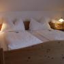 Comfortable double bed in a country inn room with wooden frame and bedside tables, illuminated by two table lamps.
