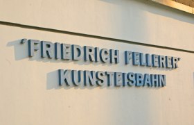 Lettering 'Friedrich Fellerer Kunsteisbahn' on a wall.